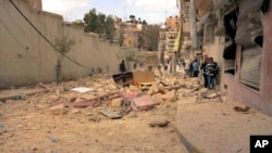 FILE - People walk amid the wreckage of damaged buildings in a street hit by shelling in Aleppo, Syria.