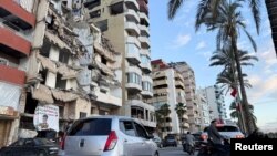 লেবাননের তাইর শহরে একটি বিধ্বস্ত ভবনের পাশ দিয়ে গাড়িগুলি যাচ্ছে। জানুয়ারি ২৪,২০২৫। 