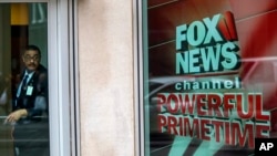 FILE - A security guard looks out of the the News Corp. headquarters in Midtown Manhattan, April 19, 2017. 
