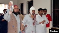 FILE - A man injured in an explosion in a Shi'ite mosque walks with relatives after receiving medical treatment at a hospital in Shikarpur, located in Pakistan's Sindh province, Jan. 30, 2015. 