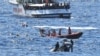 FILE - Migrants swim after jumping off the Spanish rescue ship Open Arms, close to the Italian shore in Lampedusa, Italy, Aug. 20, 2019.
