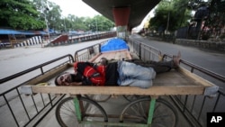Homeless men sleep on a handcart parked on a road divider in a containment zone during lockdown in Bengaluru, India, July 5, 2020. 