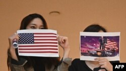 兩名香港女子在一個商場內舉行的抗議中國人大制定港版國安法的集會上手舉美國國旗和川普總統畫像。 （2020年5月28日）