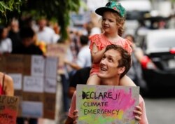 FILE - An environmental activist carries his daughter on his shoulders as they participate in a Global Climate Strike near the Ministry of Natural Resources and Environment office in Bangkok, Thailand, Sept. 20, 2019.