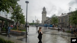 FILE - A masked woman walks in a street in Moscow, Russia, June 10, 2021, Moscow’s mayor on June 12 ordered a week off for some workplaces and imposed restrictions on many businesses to fight rising coronavirus infections.