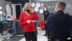 Salon owner Shelley Luther holds a citation and speaks with a Dallas police officer after she was cited for reopening her Salon A la Mode in Dallas, Texas , April 24, 2020.