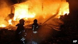 This photo provided by the Syrian Civil Defense White Helmets, which has been authenticated based on its contents and other AP reporting, shows Syrian White Helmet civil defense workers extinguishing a fire at the scene of an explosion that hit a five-story building, in the village of Sarmada, near the Turkish border, north Syria, Aug. 12, 2018. 