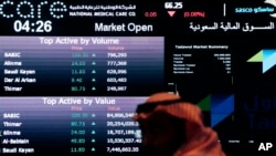 FILE - A Saudi man looks at stocks at the Tadawul Saudi Stock Exchange, in Riyadh, Saudi Arabia, June 15, 2015.