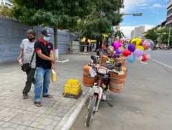 Soeung Tha sells balloons in front of Phnom Penh’s Lanka Temple, Dec. 7, 2020. (Aun Chhengpor/VOA Khmer)