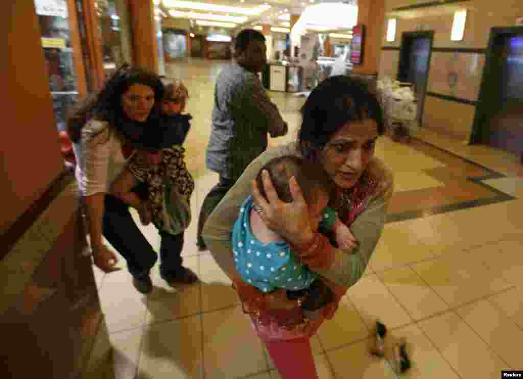 Women carrying children run for safety as armed police hunt for gunmen who went on a shooting spree in Westgate Shopping Center in Nairobi, Sept. 21, 2013. 