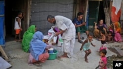 A Rohingya refugee distributes wheat, donated by locals, among other refugees at a camp for the refugees in New Delhi, India. 
