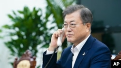 In this photo provided by South Korea Presidential Blue House, South Korean President Moon Jae-in talks with New Zealand Prime Minister Jacinda Ardern on the phone at the presidential Blue House in Seoul, South Korea, July 28, 2020.