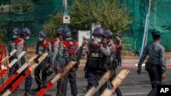 ตำรวจเมียนมาถ่ายภาพผู้ชุมนุมต่อต้านการรัฐประหารในนครย่างกุ้ง เมื่อ 24 กุมภาพันธ์ 2021 (ที่มา: AP)