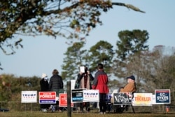 FILE - Poll workers assist voters on a brisk fall morning at the Efland Ruritan Club polling site in Efland, N.C., Nov. 3, 2020.