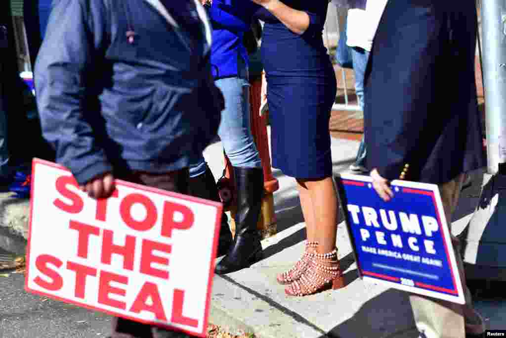 Trump supporters carry a "Stop the Steal" and campaign sign after Democratic presidential nominee Joe Biden overtook President Donald Trump in the Pennsylvania general election vote count, in Philadelphia, Pennsylvania, Nov. 6, 2020.
