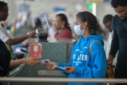 FILE - A passenger wears a mask as she waits at passport control in Bole International Airport in Addis Ababa, Jan. 30, 2020, following an outbreak of coronavirus in China.