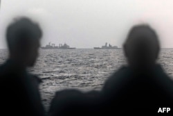 This photo taken on Feb. 13, 2025, and released by the Australian military shows sailors on the Royal Australian Navy ship HMAS Arunta looking at the Chinese Fuchi-class replenishment vessel and Weishanhu Jiangkai-class frigate Hengyang in the Tasman Sea.
