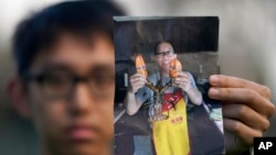 মুক্তিপ্রাপ্ত তিনজনের একজন, কাই লি'র পুত্র হ্যারিসন লি তার বাবার ছবি তুলে ধরছেন। ফাইল ফটোঃ ২৩ জানুয়ারি, ২০২৪। 