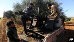 Des combattants syriens soutenus par la Turquie chargent des munitions sur une ligne de front près de la ville de Saraqib dans la province d'Idlib, en Syrie, mercredi, février. 26, 2020.