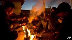 Afghan refugees gather around a fire to warm themselves in the early hours while waiting to get on board a ferry traveling to Athens, at the port of Mitylene on the northeast Greek island of Lesbos, Oct. 9, 2015.
