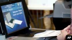 A Madison County voter slides her paper ballot into a counting machine, Nov. 6, 2018 in Ridgeland, Mississippi. 