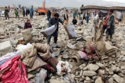 Afghan men search for their belongings after floods in Charikar, capital of Parwan province, Afghanistan, Aug. 26, 2020.