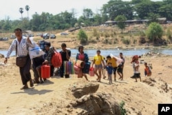 FILE - People cross the Moei River as they flee Myawaddy township in Myanmar to Thailand's Mae Sot town in Thailand's Tak province on April 20, 2024.