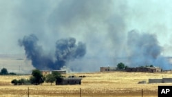 FILE - In this photo taken in Akcakale, Sanliurfa province, southeastern Turkey, smoke from a U.S.-led airstrike can be seen rising over the outskirts of Tal Abyad, Syria, June 14, 2015. 