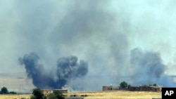 In this photo taken in Akcakale, Sanliurfa province, southeastern Turkey, from the Turkish side of the border between Turkey and Syria, smoke from a U.S.-led airstrike rises over the outskirts of Tal Abyad, Syria, June 14, 2015. 