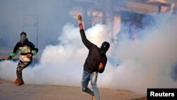 A demonstrator hurls a stone amidst smoke from tear gas fired by Indian policemen during a protest in Kashmir, in Srinagar, Jan. 13, 2018. 