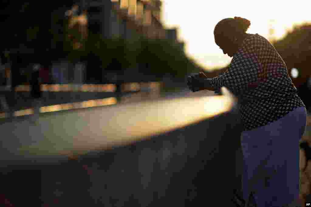 Doris Simmons stands across the street from Emanuel AME Church, the scene of last week&#39;s mass shooting, as the sun rises in Charleston, South Carolina. President Barack Obama delivered the eulogy for one of the victims, Sen. Clementa Pinckney, during his funeral Friday at a nearby college arena.