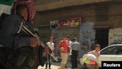 A man throws a bucket of water to put out flames from a tire set on fire in a street by rioting youths, Mombasa, Kenya, Oct. 4, 2013. 