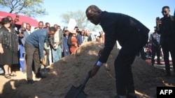 Botswana President Duma Boko throws sand onto the grave during the burial and memorial service of the late Pitseng Gaoberekwe in Metsiamanong village, Central Kalahari Game Reserve (CKGR), on Dec. 10, 2024.
