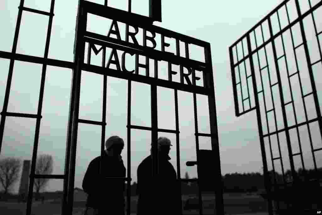 People walk through the gate of the Sachsenhausen Nazi death camp with the phrase &#39;Arbeit macht frei&#39; (work sets you free) at the eve of the International Holocaust Remembrance Day, in Oranienburg, about 30 kilometers, (18 miles) north of Berlin, Jan. 26, 2015.