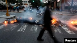 A man walks past a barricade set by anti-government protesters at Altamira square in Caracas, March 6, 2014.