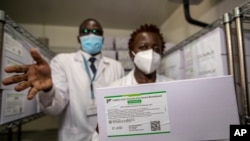 Technicians show a carton of AstraZeneca COVID-19 vaccine manufactured by the Serum Institute of India, inside a cold storage room at the central vaccine depot in Kitengela town on the outskirts of Nairobi, Kenya, March 4, 2021.