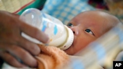 Cambodian orphan is fed formula milk by a nanny at Chrey Chao commune orphanage on the outskirts of Phnom Penh, May 12, 2004.
