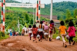 In this photo taken on June 10, 2021 people carry food aid distributed by a volunteer group in Pankai village in Kutkai township in Myanmar's eastern Shan state.