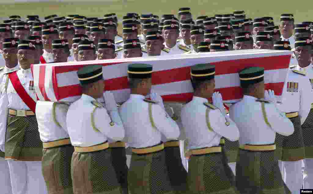 An honor guard stands by as the remains of a passenger of downed Malaysia Airlines MH17 is carried during a repatriation ceremony at KLIA airport in Sepang, Aug. 22, 2014.