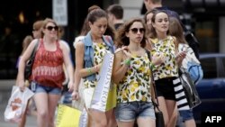 FILE - Consumers hold shopping bags as they walk along Michigan Avenue on July 29, 2016 in Chicago, Illinois. A study reports that the likelihood that young adults will earn more than their parents has plummeted in recent decades.