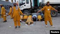 FILE - Adherents of religious and political party Jamiat Ulema-i-Islam-Fazal stand guard as others offer prayers during an Azadi (Freedom) March protesting the policies of the government of Prime Minister Imran Khan, in Islamabad, Pakistan, Nov. 2, 2019. 