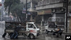 Syrian residents pull a truck that has run out of gas in Aleppo’s Sukari district, Dec. 7, 2012.