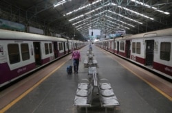 A man wearing a mask walks through a deserted train station in Mumbai, India, March 22, 2020.