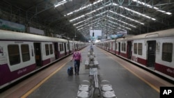 A man wearing a mask walks through a deserted train station in Mumbai, India, March 22, 2020. 