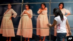 FILE - A woman adjusts cardboard boxes assembled to form a display highlighting the issue of teenage pregnancy in Mexico City, May 29, 2014.