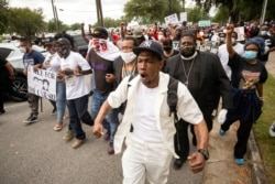 Malik Muhammad, center, joins a group of people marching from the Glynn County Courthouse in downtown to a police station after a rally to protest the shooting of Ahmaud Arbery, Saturday, May 16, 2020, in Brunswick, Ga. (AP Photo/Stephen B. Morton)
