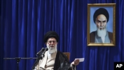 Iranian supreme leader Ayatollah Ali Khamenei delivers a speech, during a ceremony marking the 23rd death anniversary of the late revolutionary founder Ayatollah Khomeini, shown in the poster at right, at his mausoleum, just outside Tehran, Iran, June 3, 