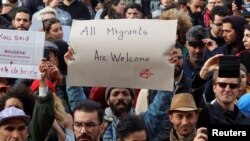 Members of rights groups carry banners during a protest, after Tunisian President Kais Saied ordered security forces to stop all illegal migration and expel all undocumented migrants, in Tunis, Tunisia Feb. 25, 2023.