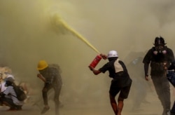 An anti-coup protester uses a fire extinguisher to provide cover for others as security forces approach their encampment in Yangon, Myanmar, March 17, 2021.