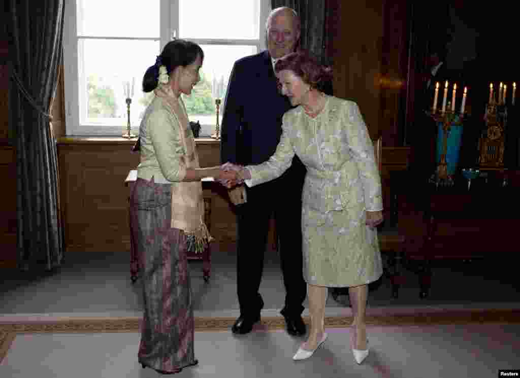 Nobel Peace Prize laureate Aung San Suu Kyi is greeted by Norwegian King Harald and Norway&#39;s Queen Sonja (L-R) at the Royal Castle in Oslo, June 16, 2012.